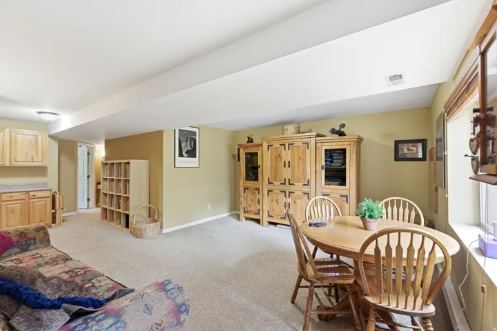 Spacious room featuring neutral carpeting, a built-in wooden cabinet, and a window with wood trim