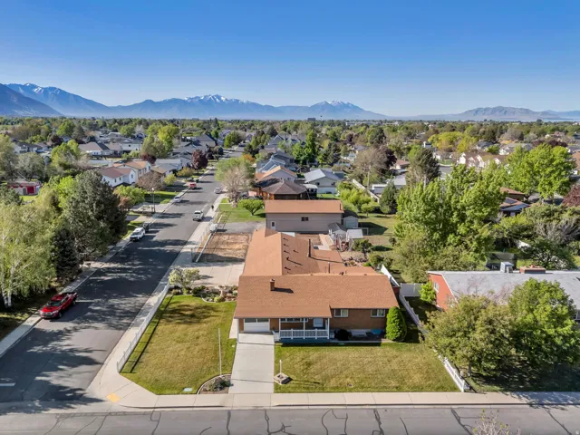 Aerial perspective showcasing the residential street, a brick exterior, a driveway, a front lawn, and mature landscaping
