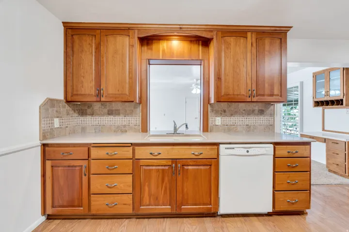 Kitchen workspace featuring wood cabinetry, light-toned countertops, and a neutral tile backsplash