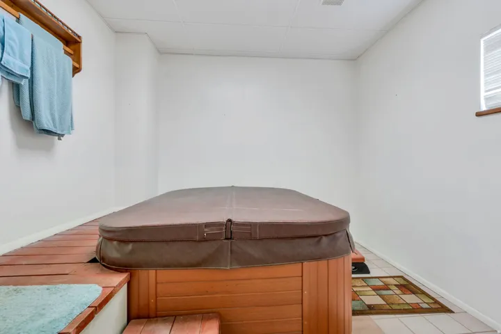 Built-in hot tub with wood-finish surround, elevated platform, and white wall finishes