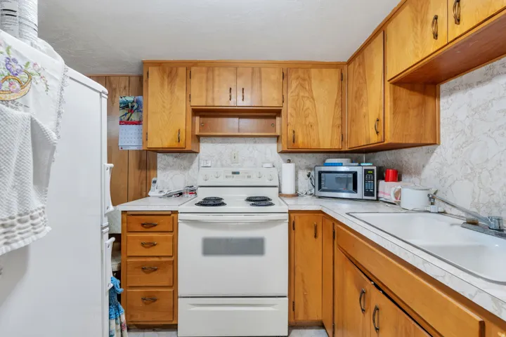 Kitchen featuring wood cabinetry, white laminate countertops, and a white electric range
