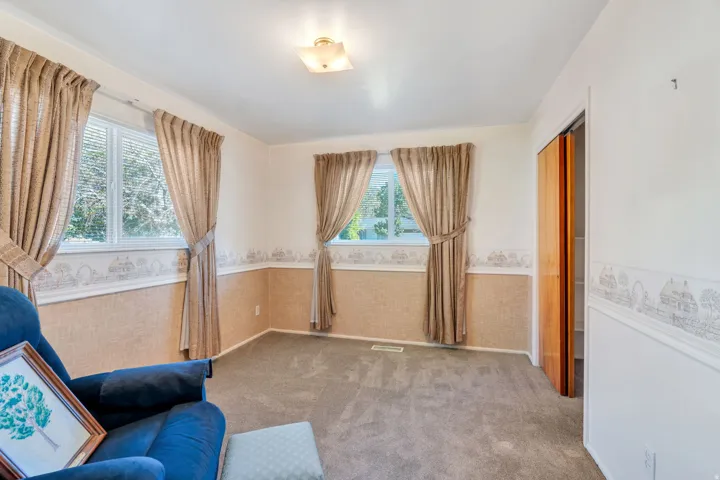 Carpeted room featuring two windows with horizontal blinds, a ceiling-mounted light fixture, and a bi-fold closet door