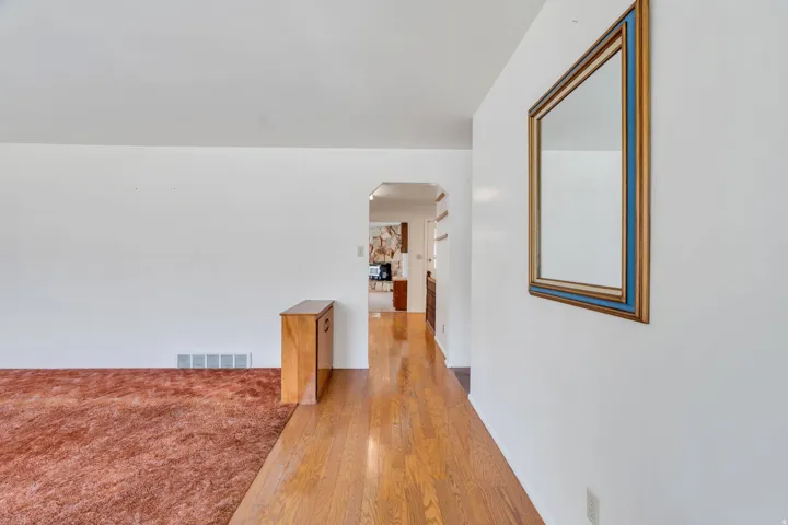 Hardwood flooring extends through the entryway, complemented by white walls and a framed mirror