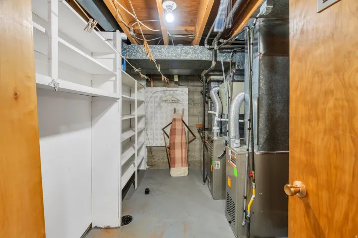 Utility area featuring multiple built-in shelving units, concrete flooring, exposed ceiling joists, and a visible HVAC system