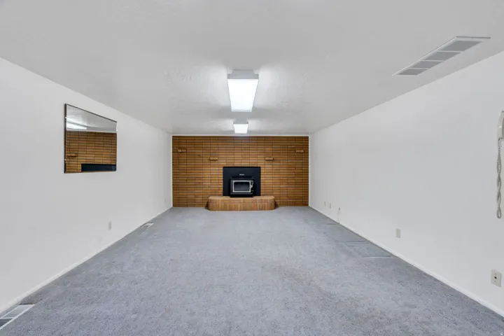 Spacious room featuring a brick accent wall with a built-in fireplace