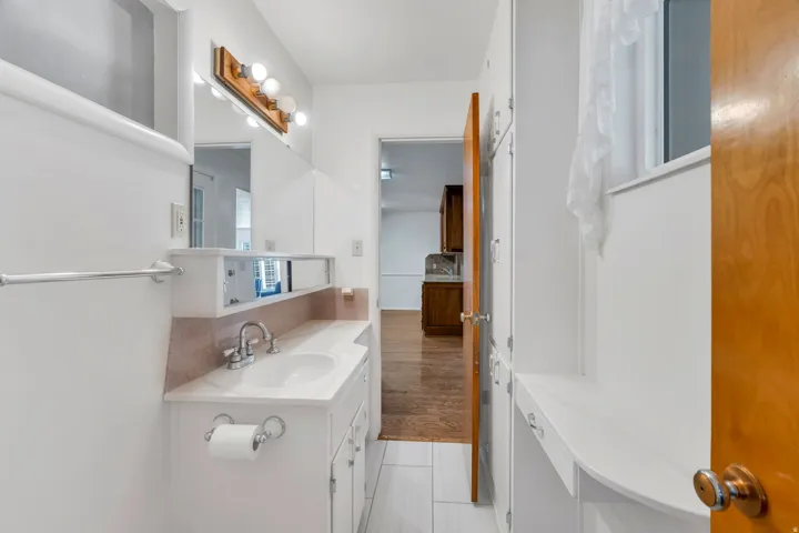 Bathroom vanity with integrated sink, chrome faucet, and mirrored medicine cabinet