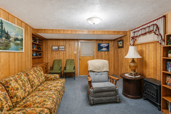 Paneled walls featuring a built-in shelving unit, a ceiling-mounted light fixture, and a window with blinds