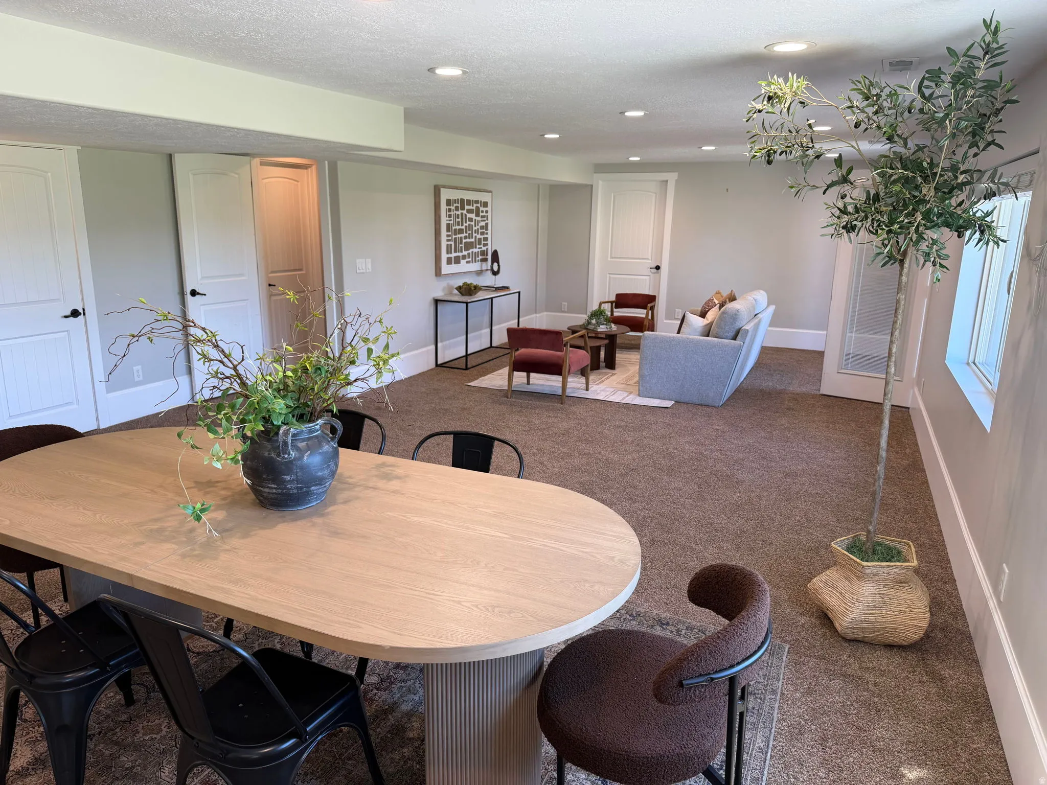 Spacious open-concept room featuring recessed lighting, light gray walls, white trim, and doors with black hardware