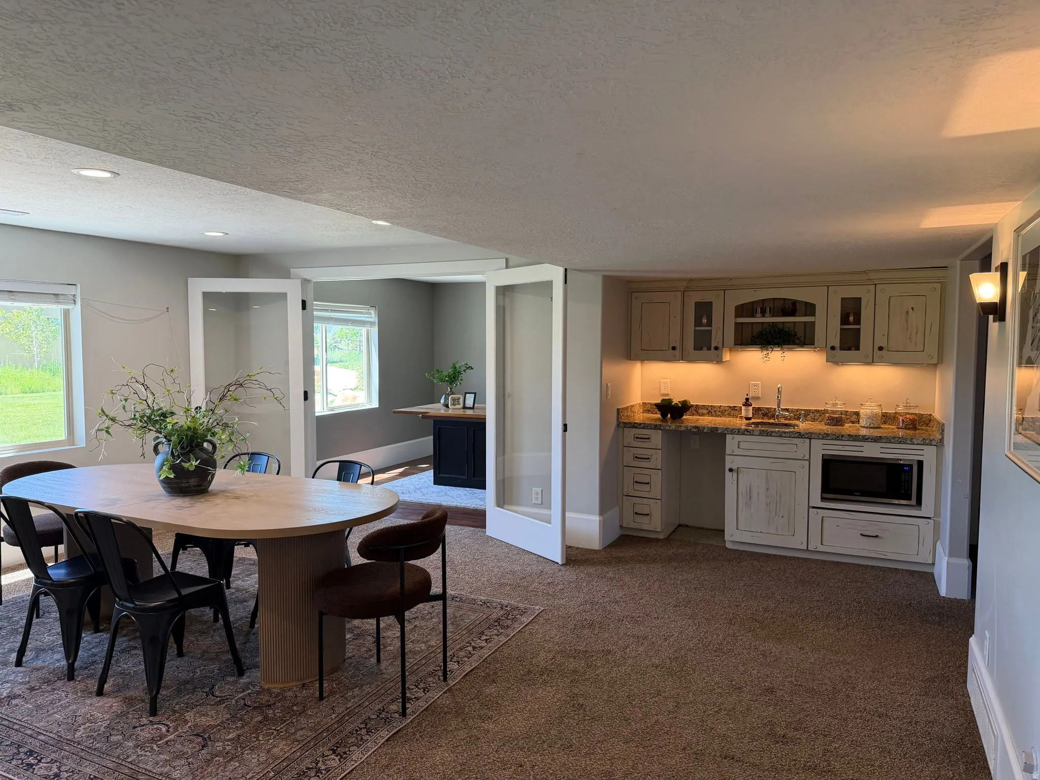 Well-appointed wet bar featuring light-colored cabinetry, granite-style countertops, and a built-in microwave