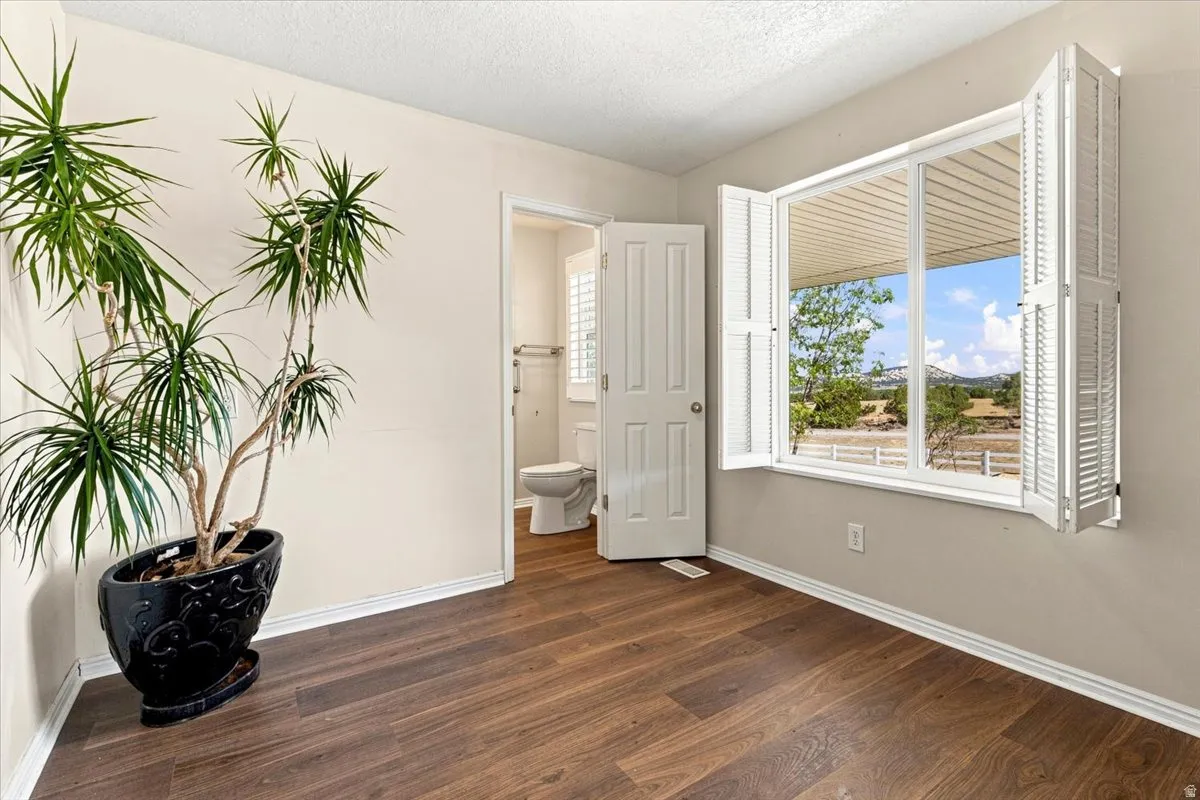 Wood-finish flooring, white window shutters, and a white interior door