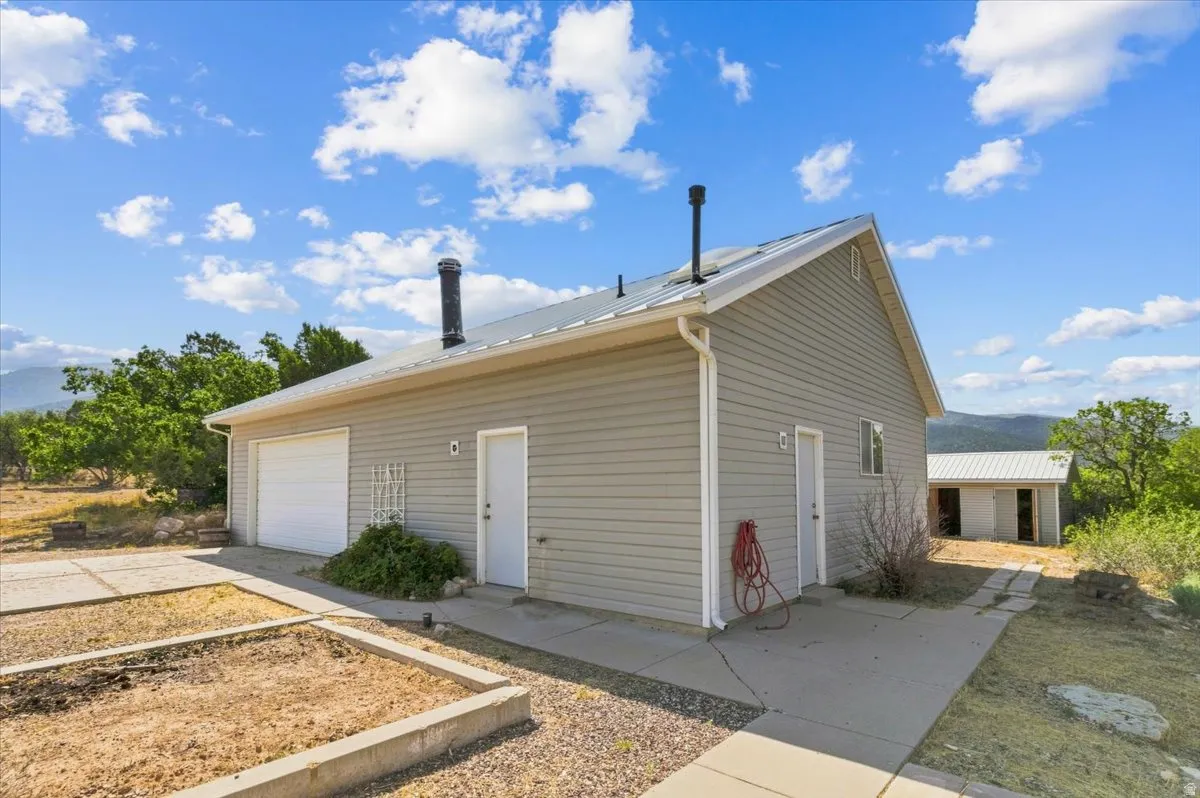 Siding exterior with a metal roof, attached garage, and multiple entry doors