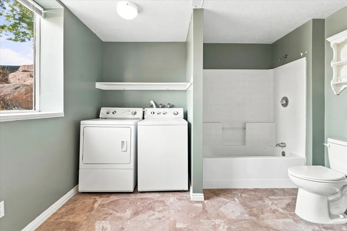 Tile-finish flooring with a white built-in bathtub, a window, and an overhead light fixture