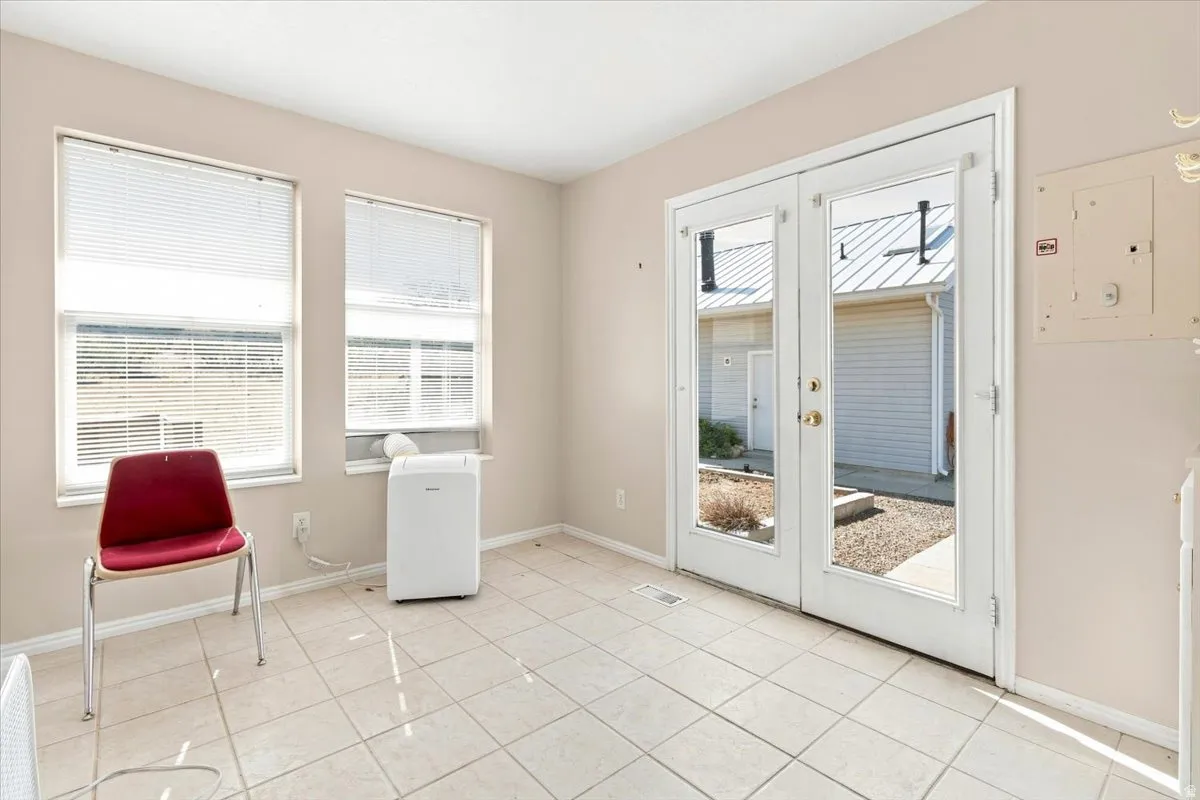Light tile flooring, dual windows, and a set of French doors