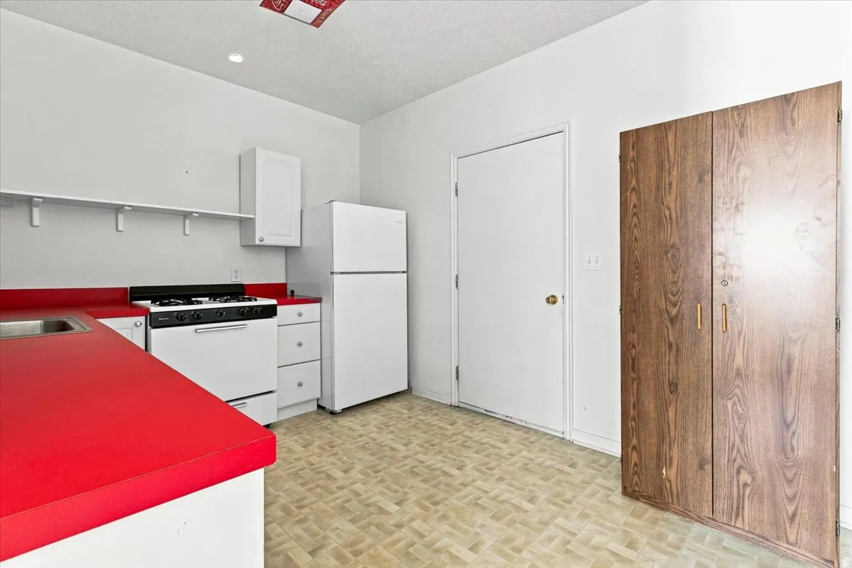 Kitchen featuring white appliances, red countertops, and wood-finish cabinetry