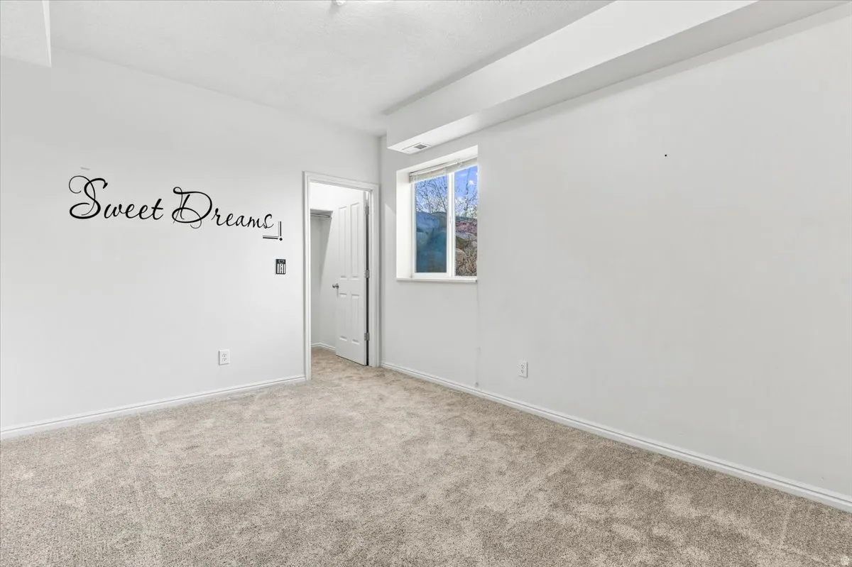 Light-colored wall-to-wall carpeting, white painted walls, and a single window with white trim