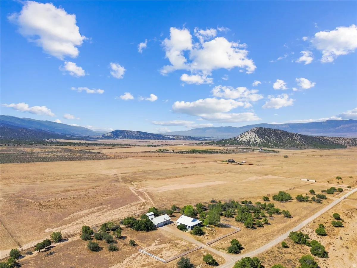 Expansive terrain with distant mountains, featuring a detached structure and established trees