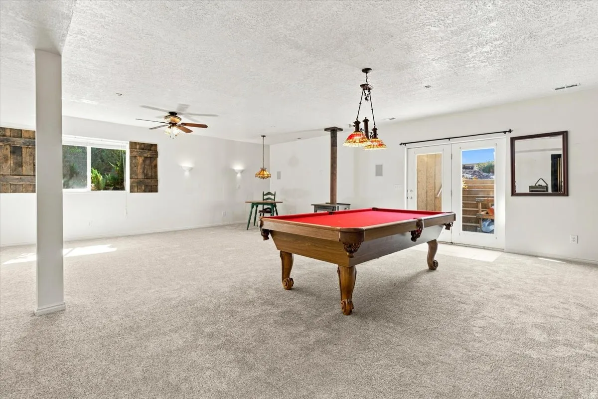 Spacious room featuring light-toned carpeting, a ceiling fan, and French doors