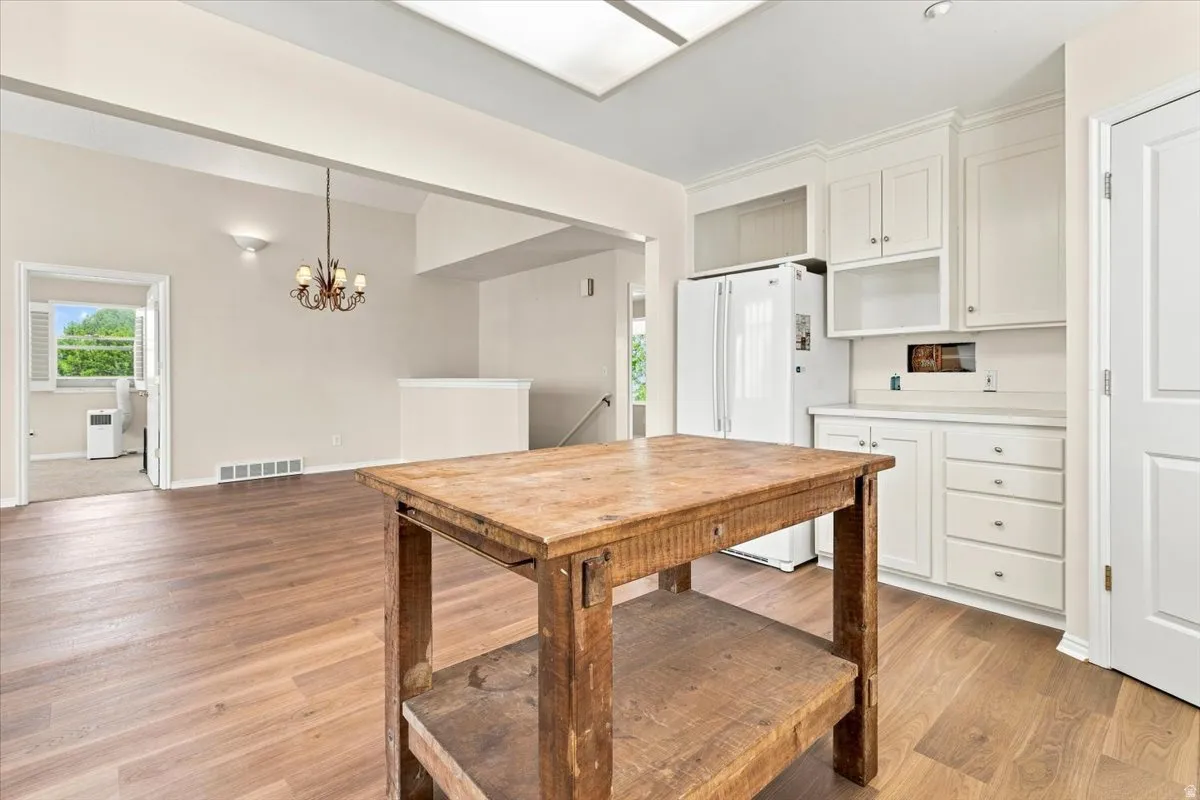 Kitchen featuring white cabinetry with crown molding, light-toned countertops, and a skylight
