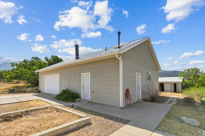 Siding exterior with a metal roof, attached garage, and multiple entry doors