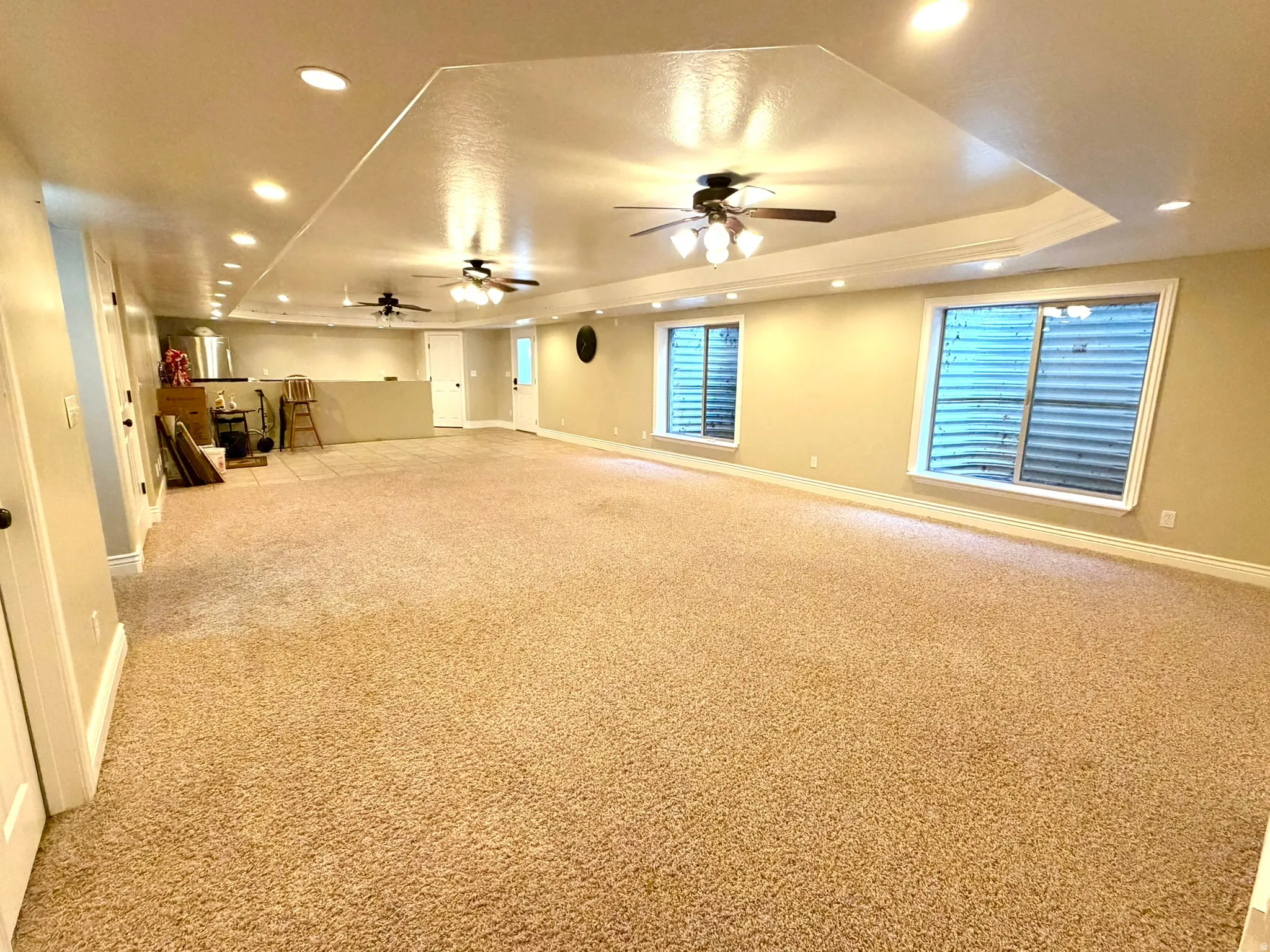Spacious open-concept room featuring plush carpet flooring, recessed lighting, and multiple ceiling fans
