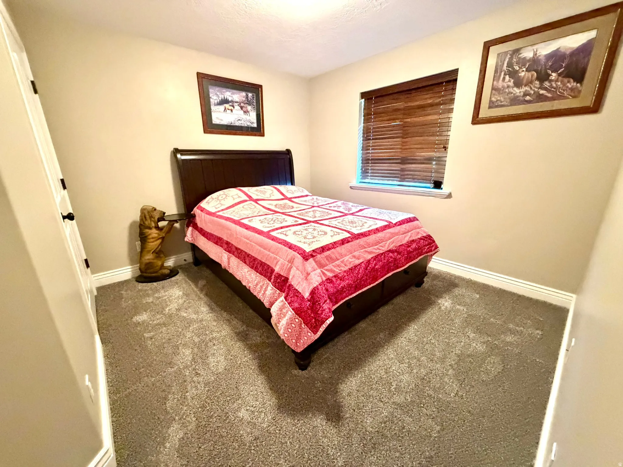Spacious room featuring neutral wall tones, carpeting, white baseboards, and a window with wood-finish blinds