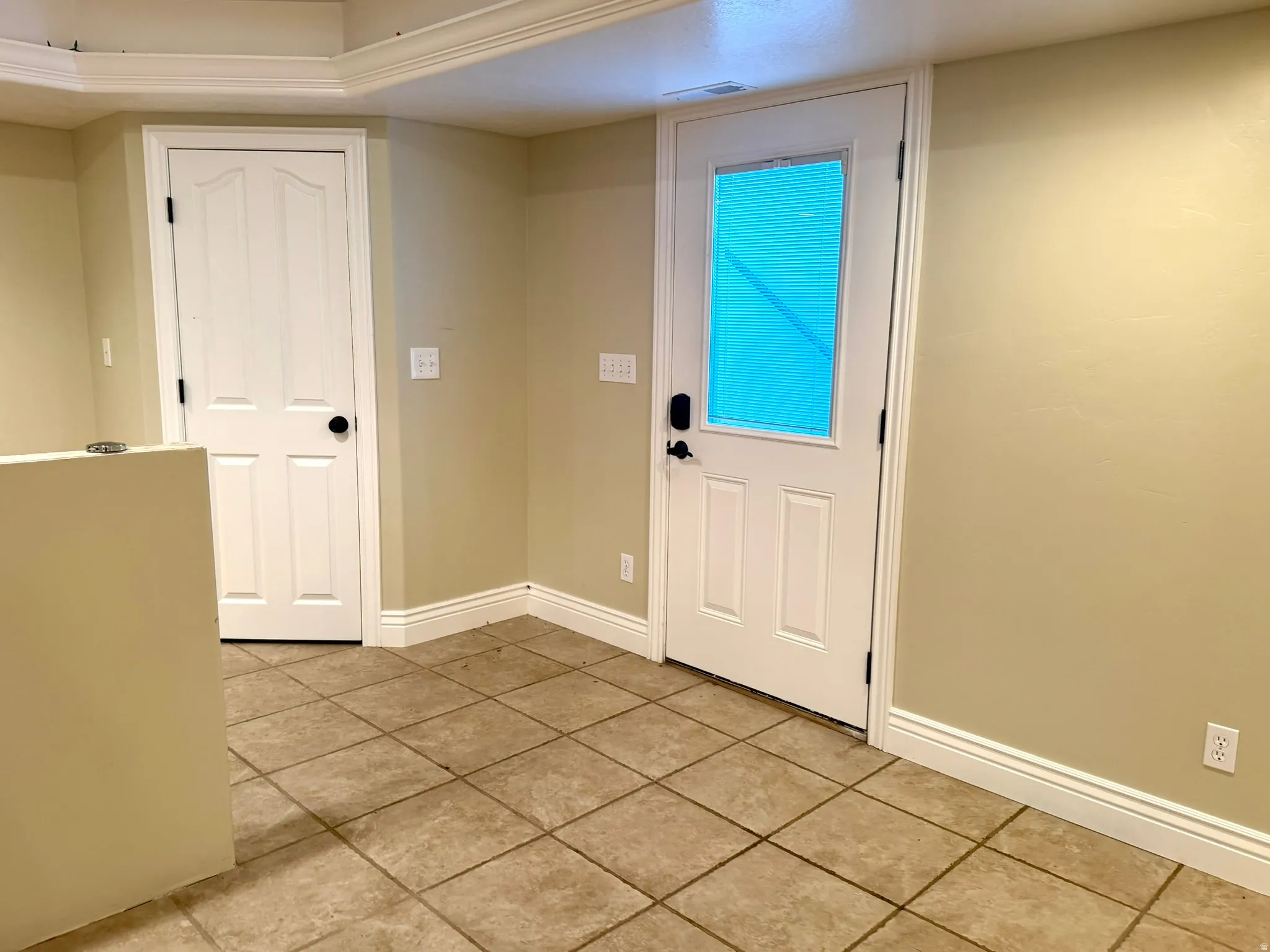 Outside entrance from back yard with tile flooring extending throughout the space
