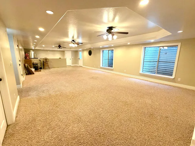 Spacious open-concept room featuring plush carpet flooring, recessed lighting, and multiple ceiling fans
