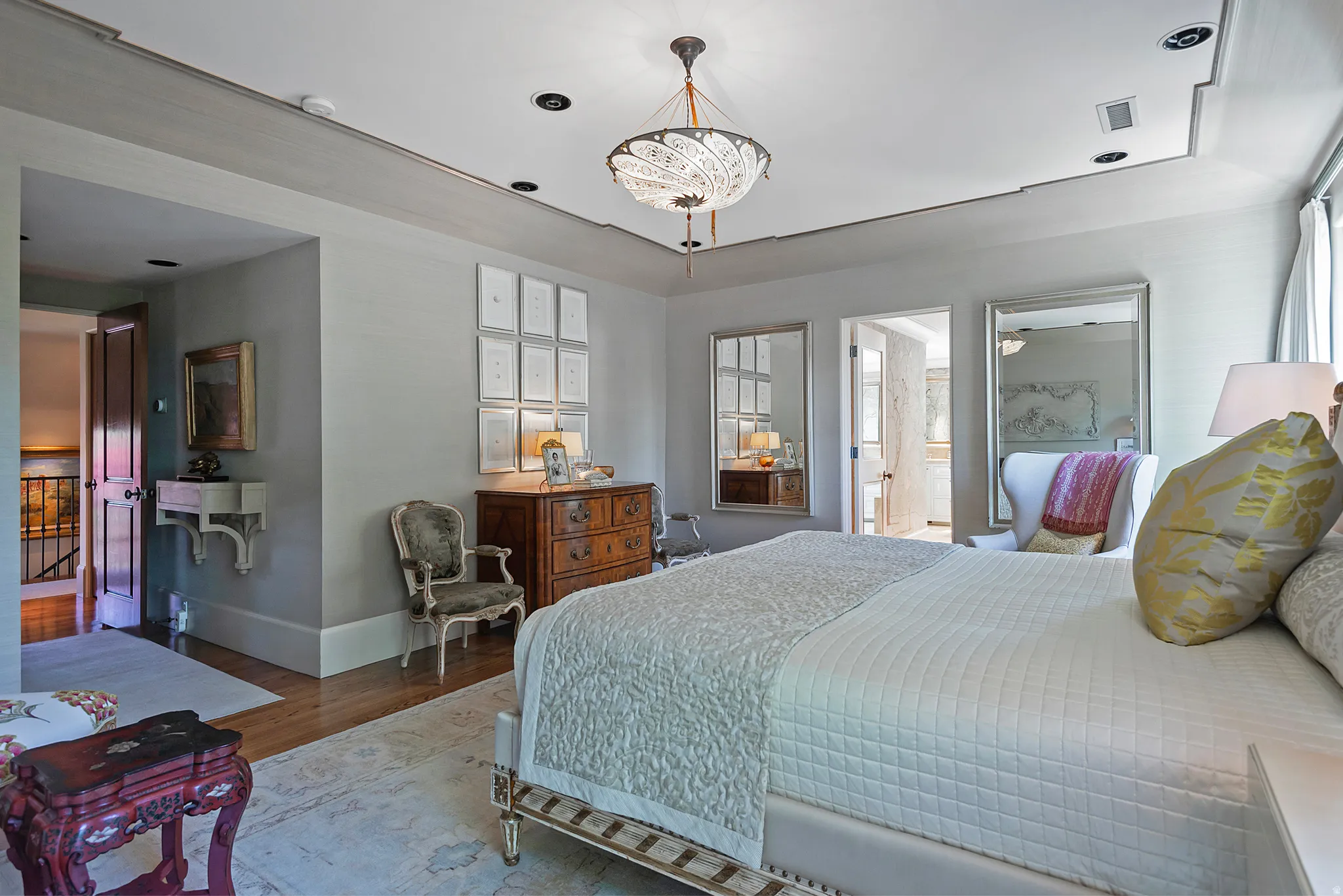 Spacious bedroom featuring decorative tray ceiling, recessed lighting, wood-finish flooring, and an en-suite bathroom entry