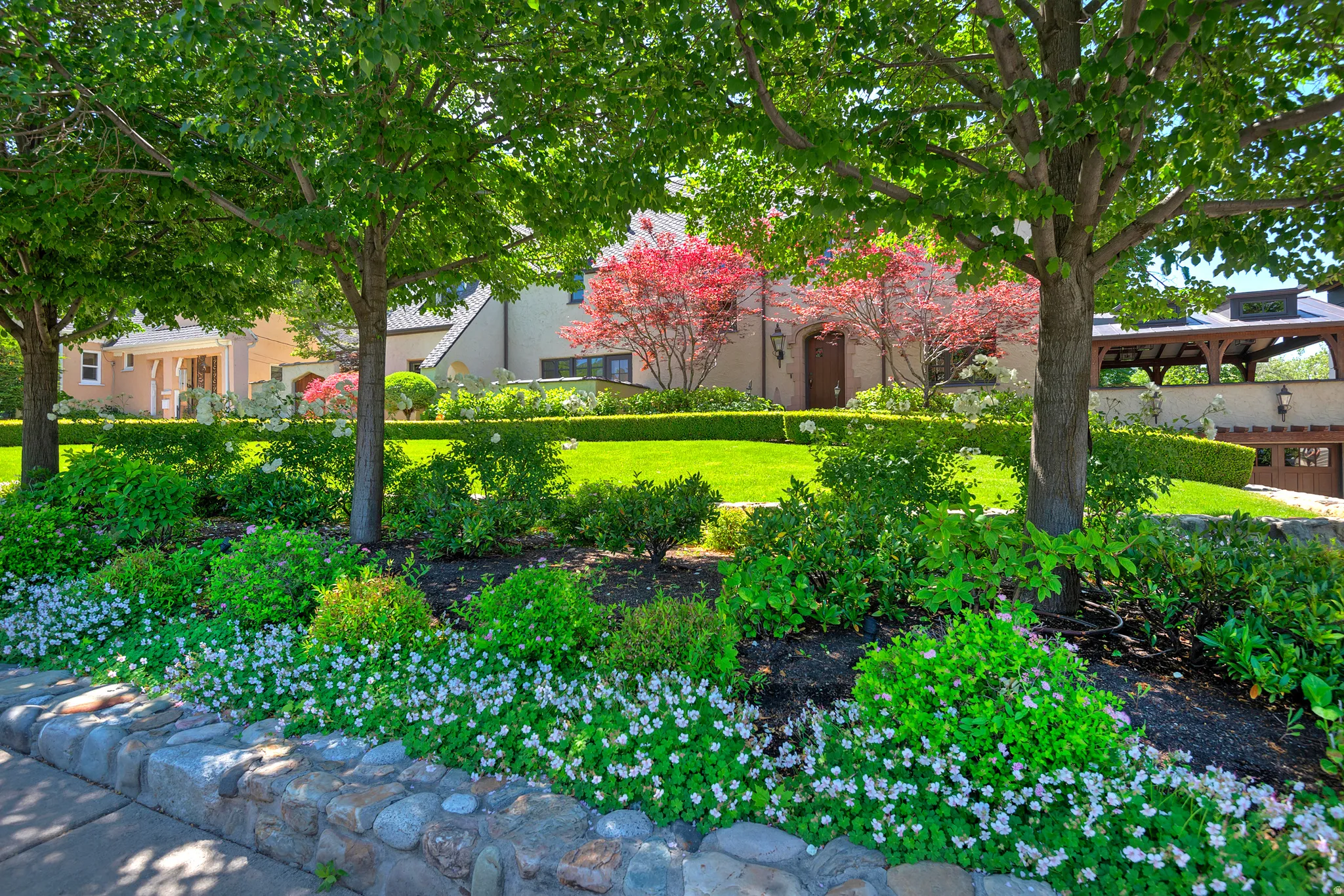 Stone retaining wall with lush landscaping and mature trees