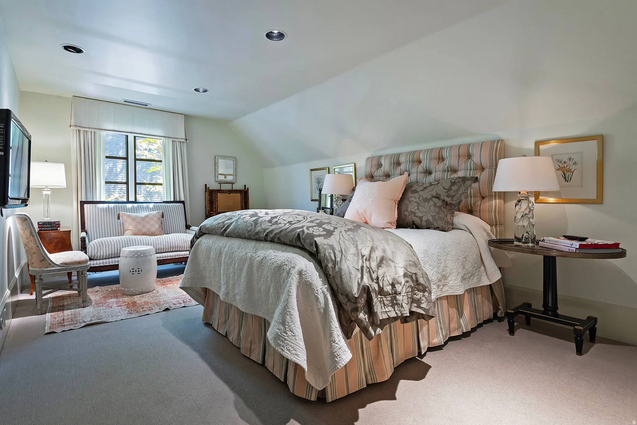 Carpeted room featuring an upholstered tufted headboard, recessed ceiling lighting, a multi-pane window with drapery, and a built-in window seat