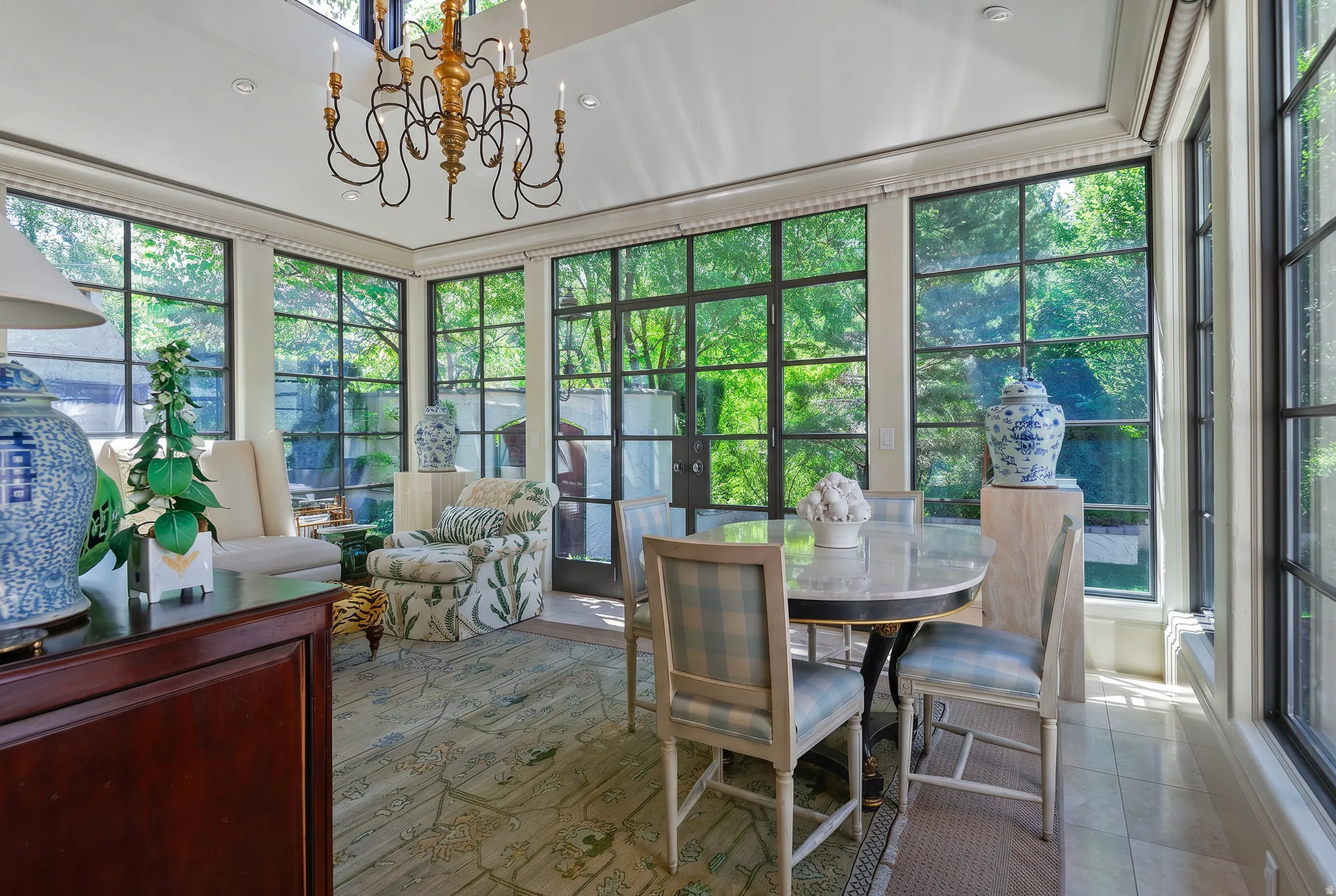 Sunroom featuring expansive grid-pane windows, a vaulted ceiling, and a decorative chandelier