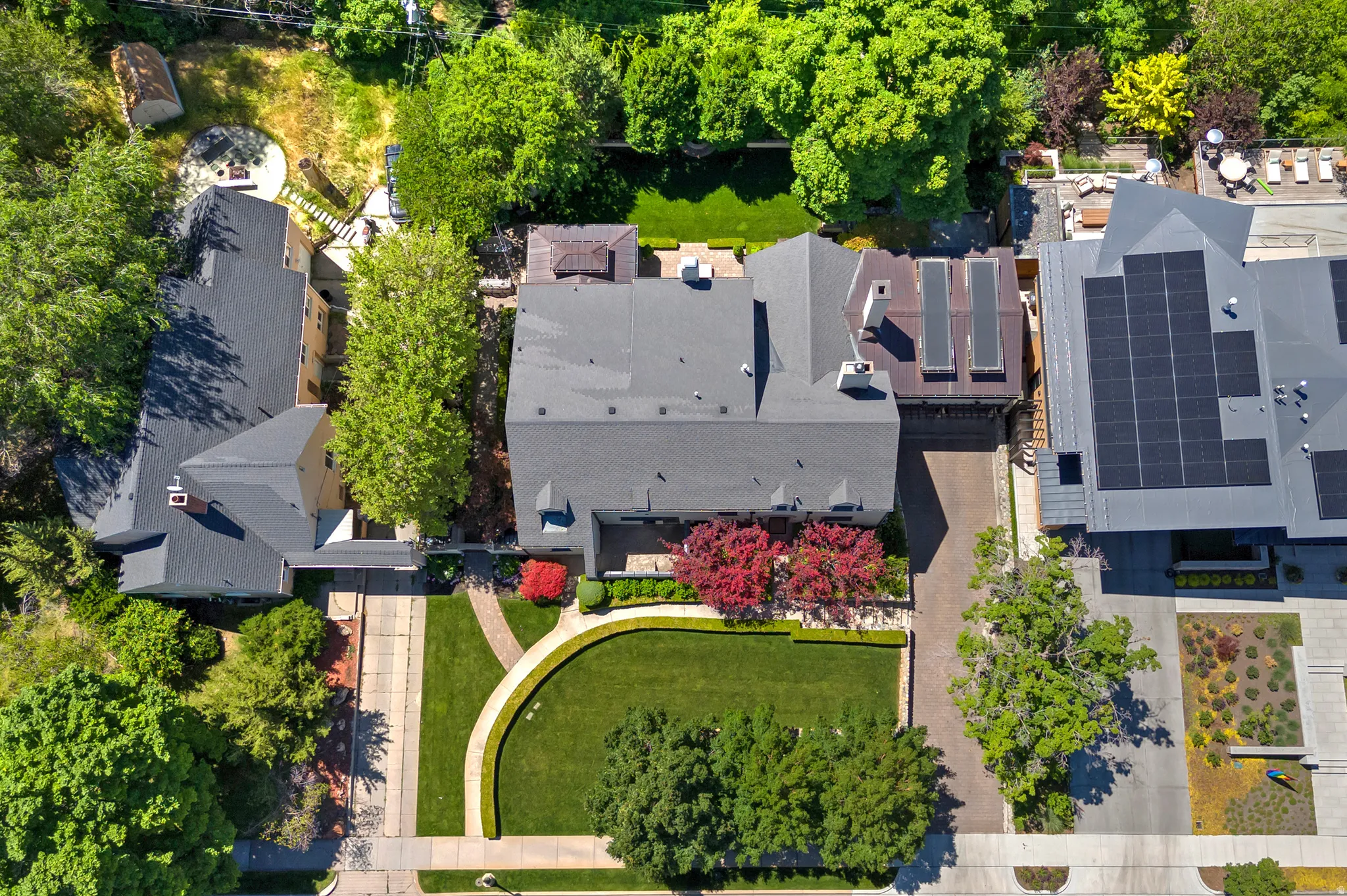 Residential property featuring a deep setback from the street, mature landscaping, a paved driveway, and a private rear yard area
