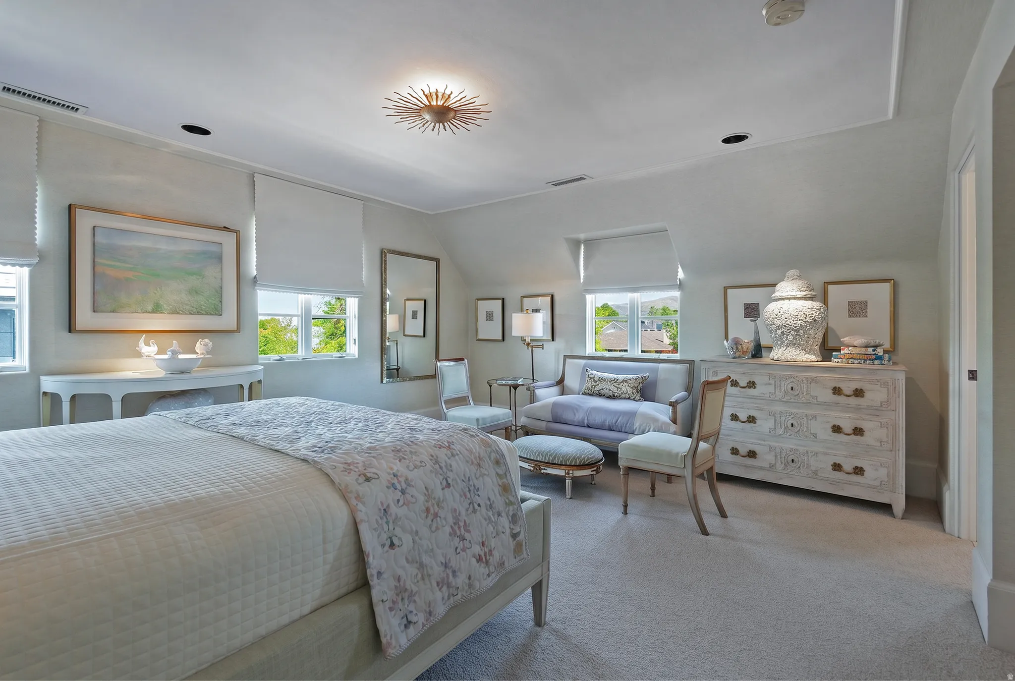 Spacious room featuring light-toned carpeting and multiple windows with white window treatments