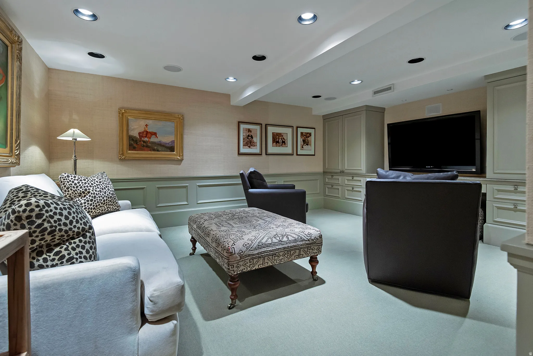 Recessed lighting illuminates a space featuring built-in cabinetry, wainscoting, and carpeted flooring