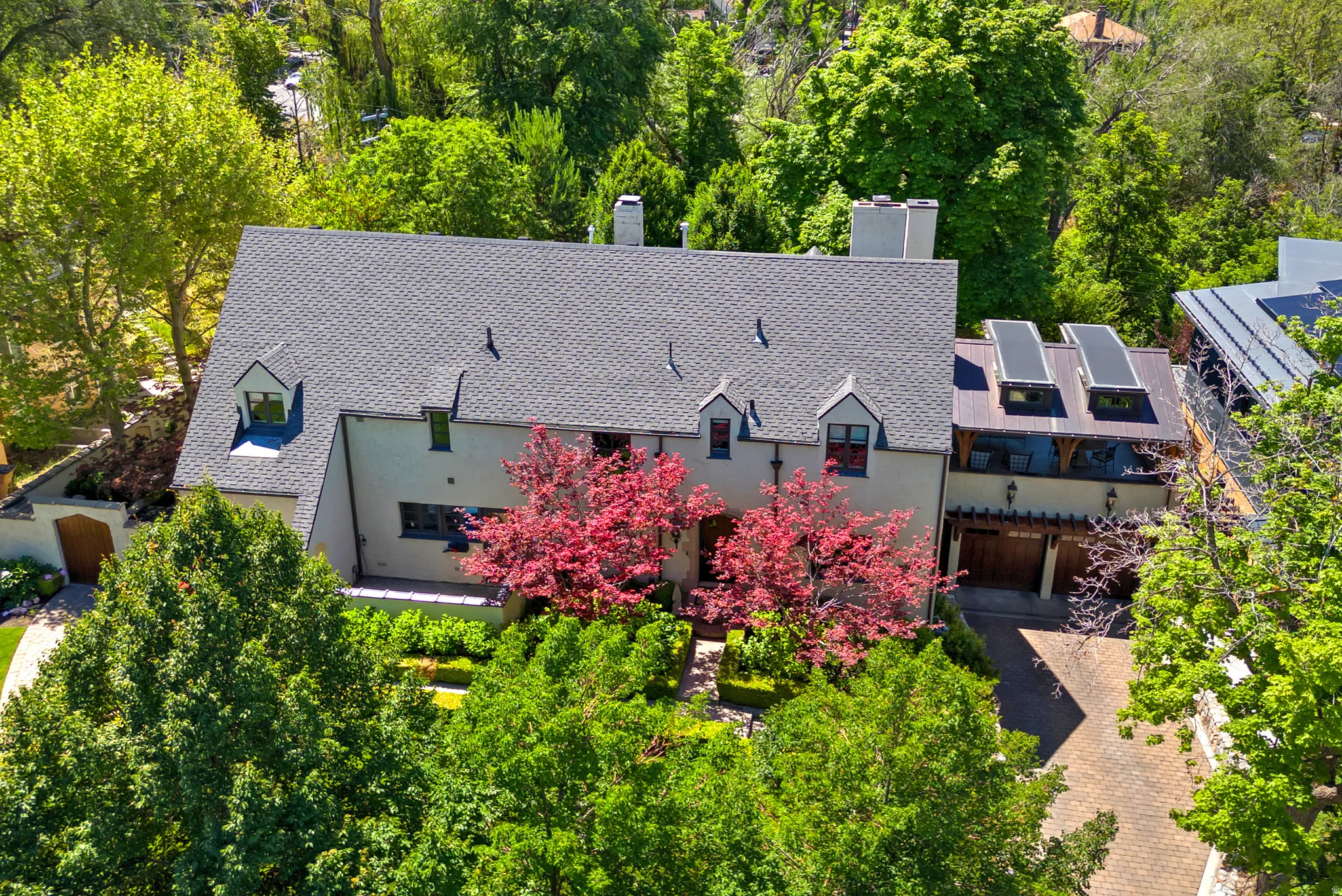 Pitched roof residence featuring dormer windows and a light-colored stucco exterior