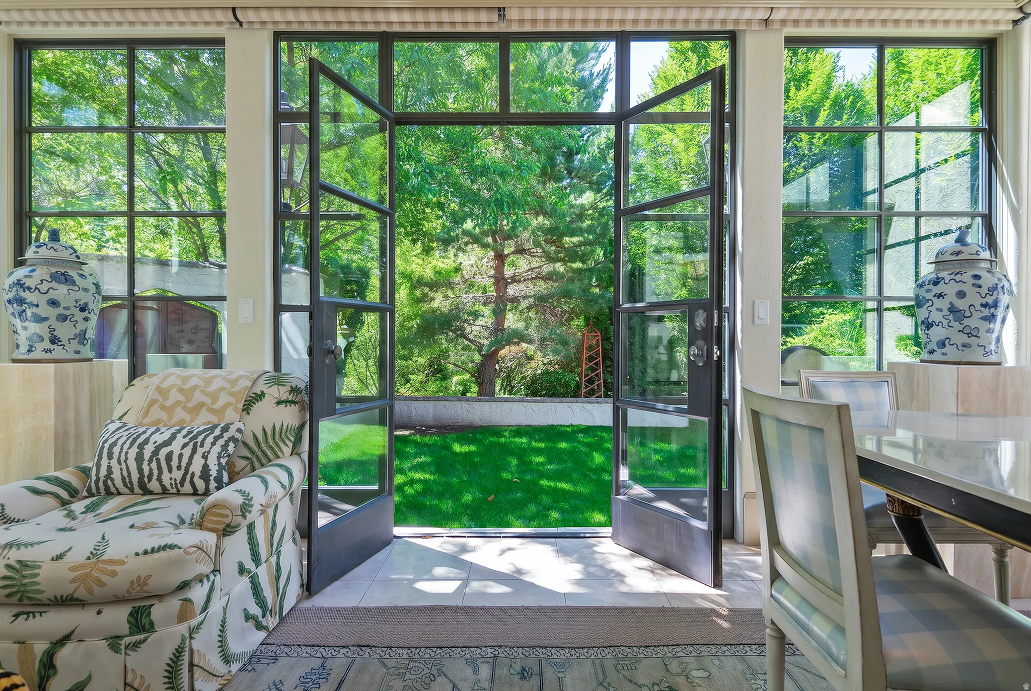 Steel-framed French doors opening to an exterior patio and green space