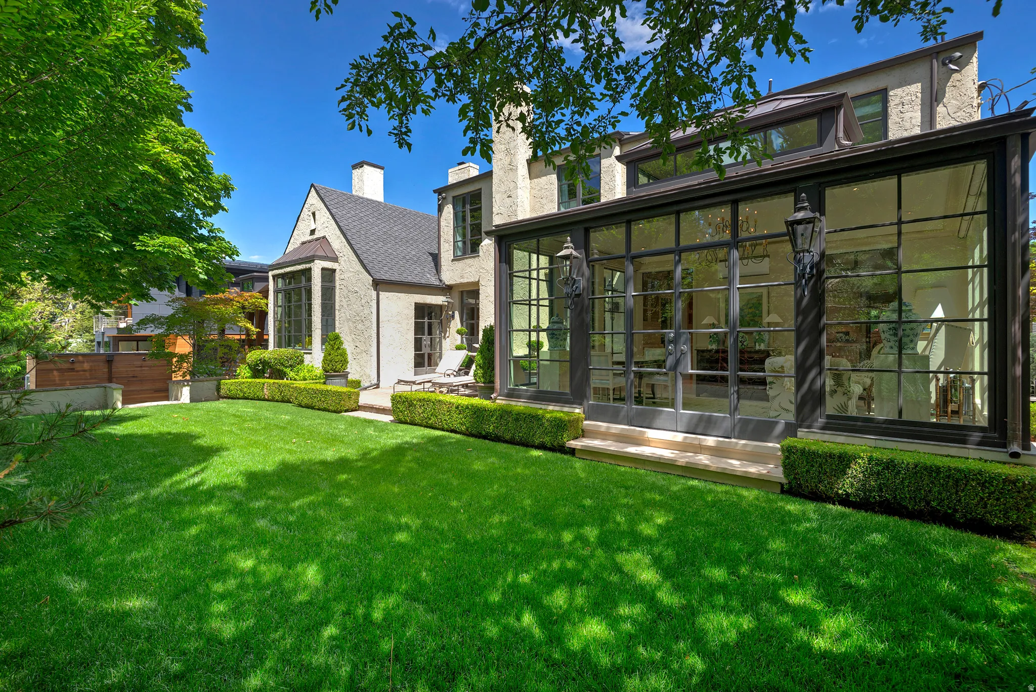 Expansive rear yard featuring a manicured lawn, established hedges, and mature trees
