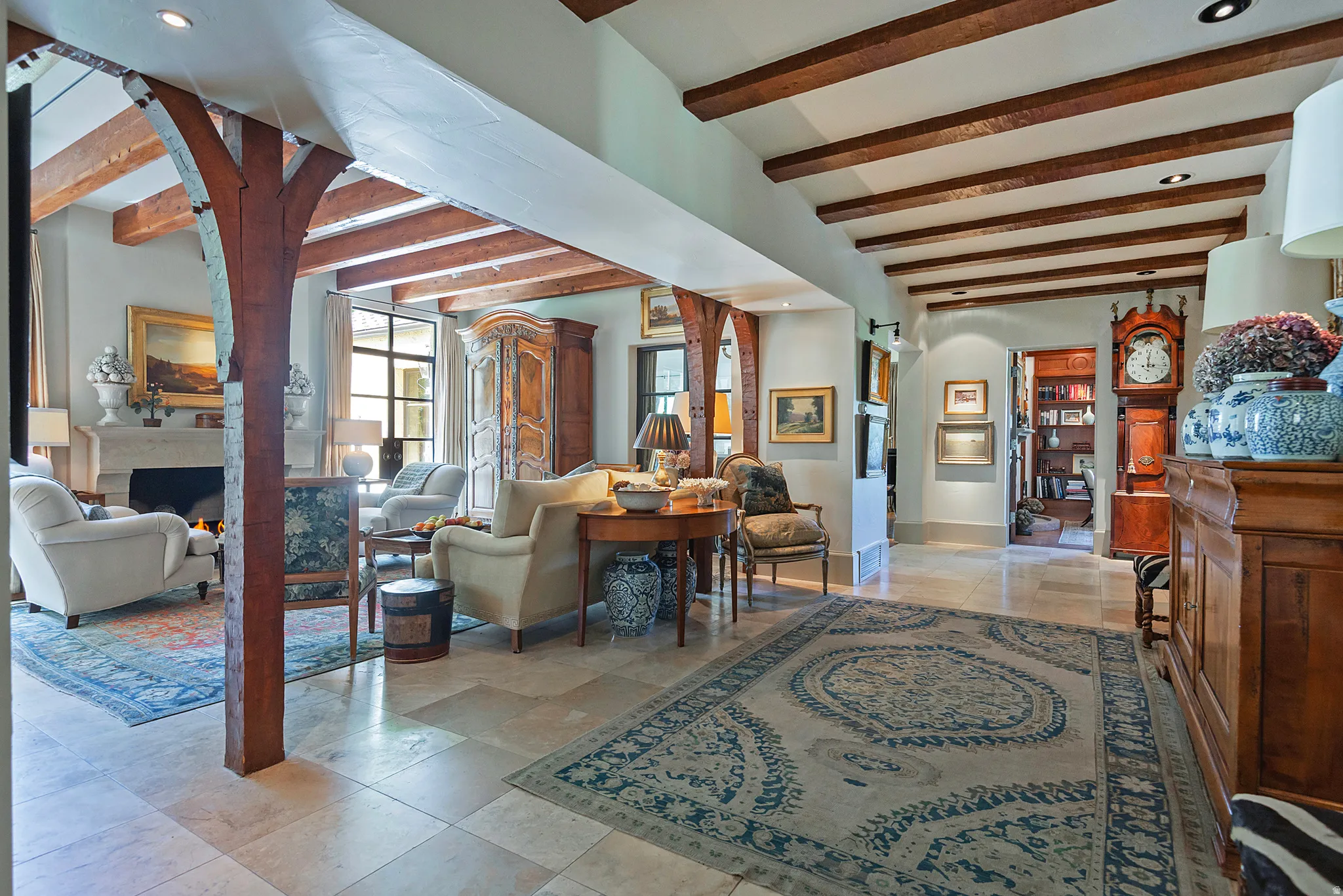 Spacious interior featuring exposed wood beams, wood columns, and light tile flooring
