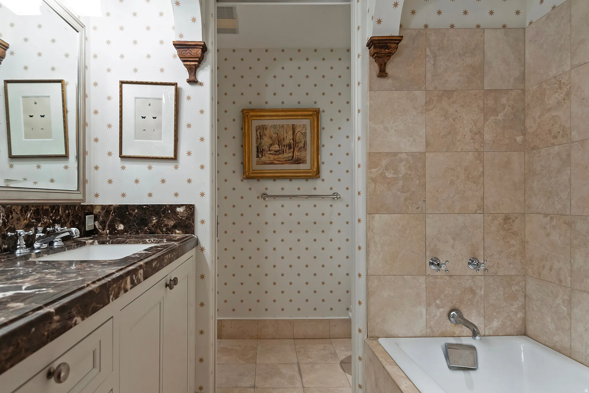 Bathroom featuring a built-in tub with tile surround, a single vanity with a dark polished stone countertop, and light-toned tile flooring