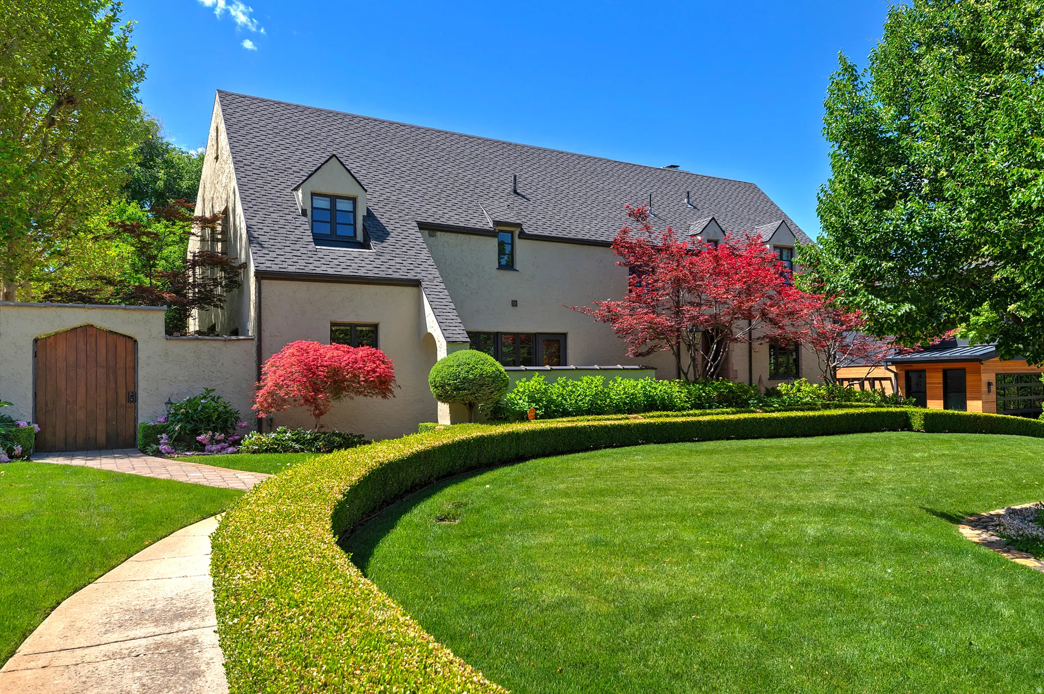 Stucco exterior residence with a dark shingle roof and multiple dormer windows
