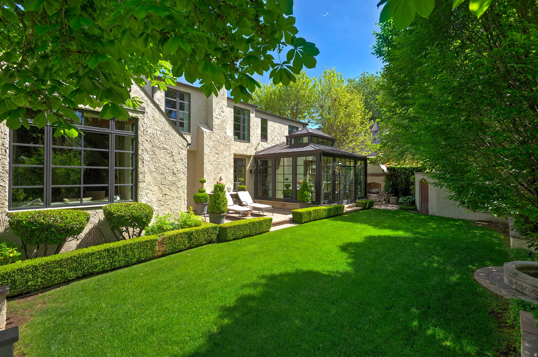Rear exterior featuring a sunroom addition with large glass panes, stucco siding, and multiple large windows
