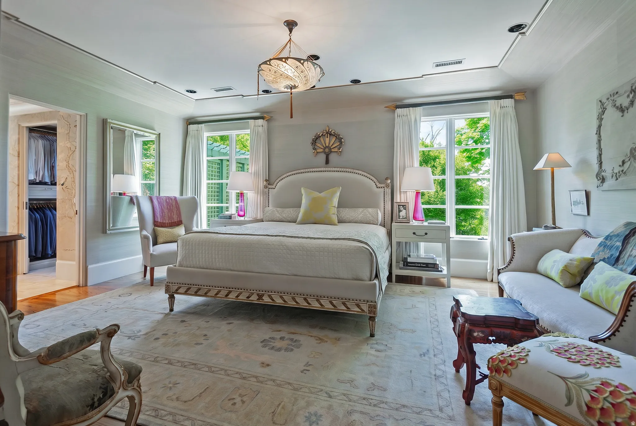 Spacious room featuring wood-finish flooring, a built-in closet with custom shelving, double windows, and a decorative ceiling light fixture