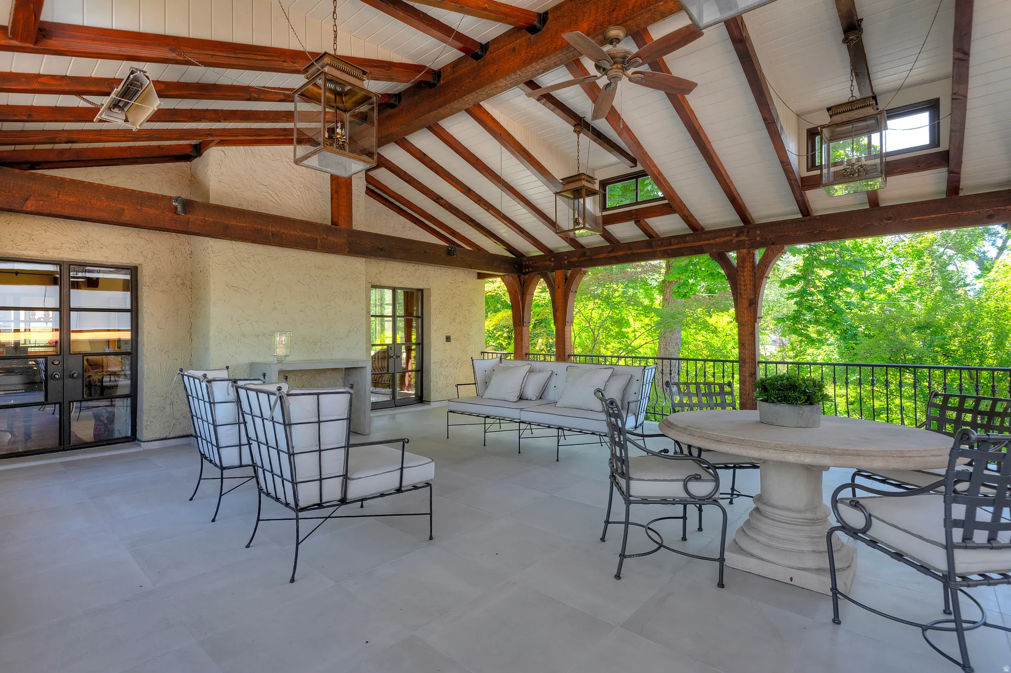 Expansive covered patio featuring an exposed beam ceiling, neutral-toned tile flooring, and a stucco wall finish