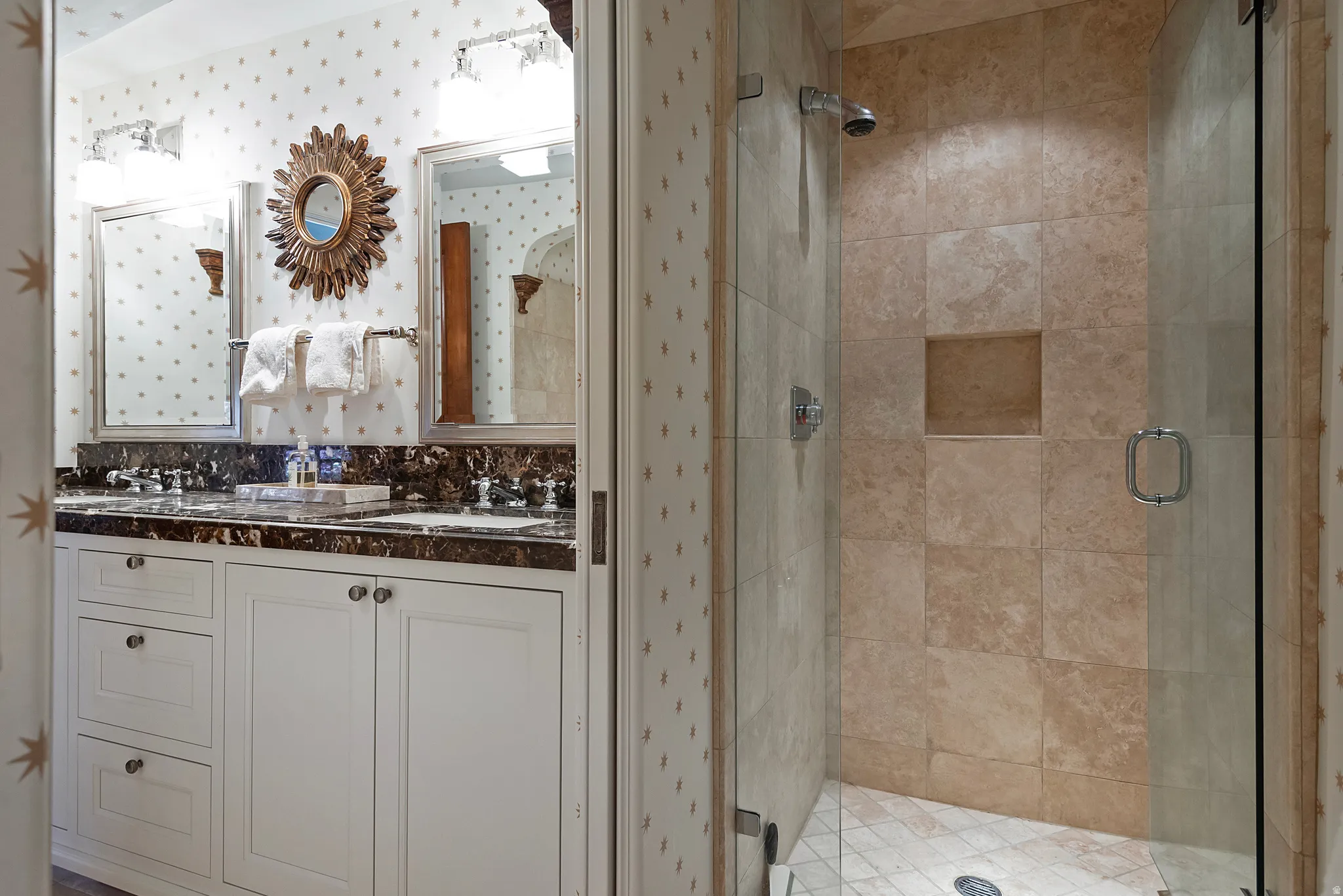 Bathroom featuring a dual vanity with a dark countertop, white cabinetry, and two framed mirrors