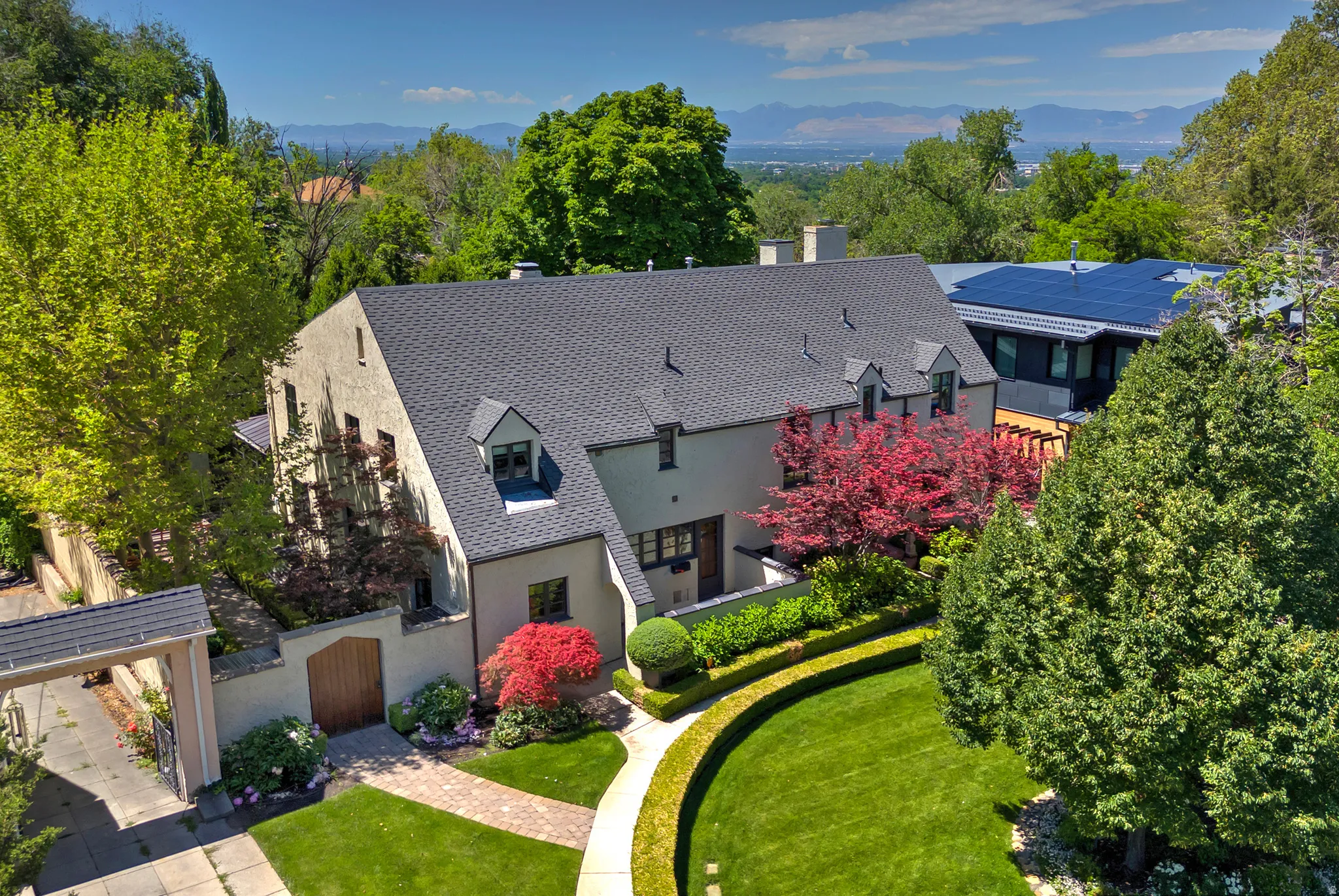 Stucco exterior residence with a dark shingle roof and multiple dormer windows