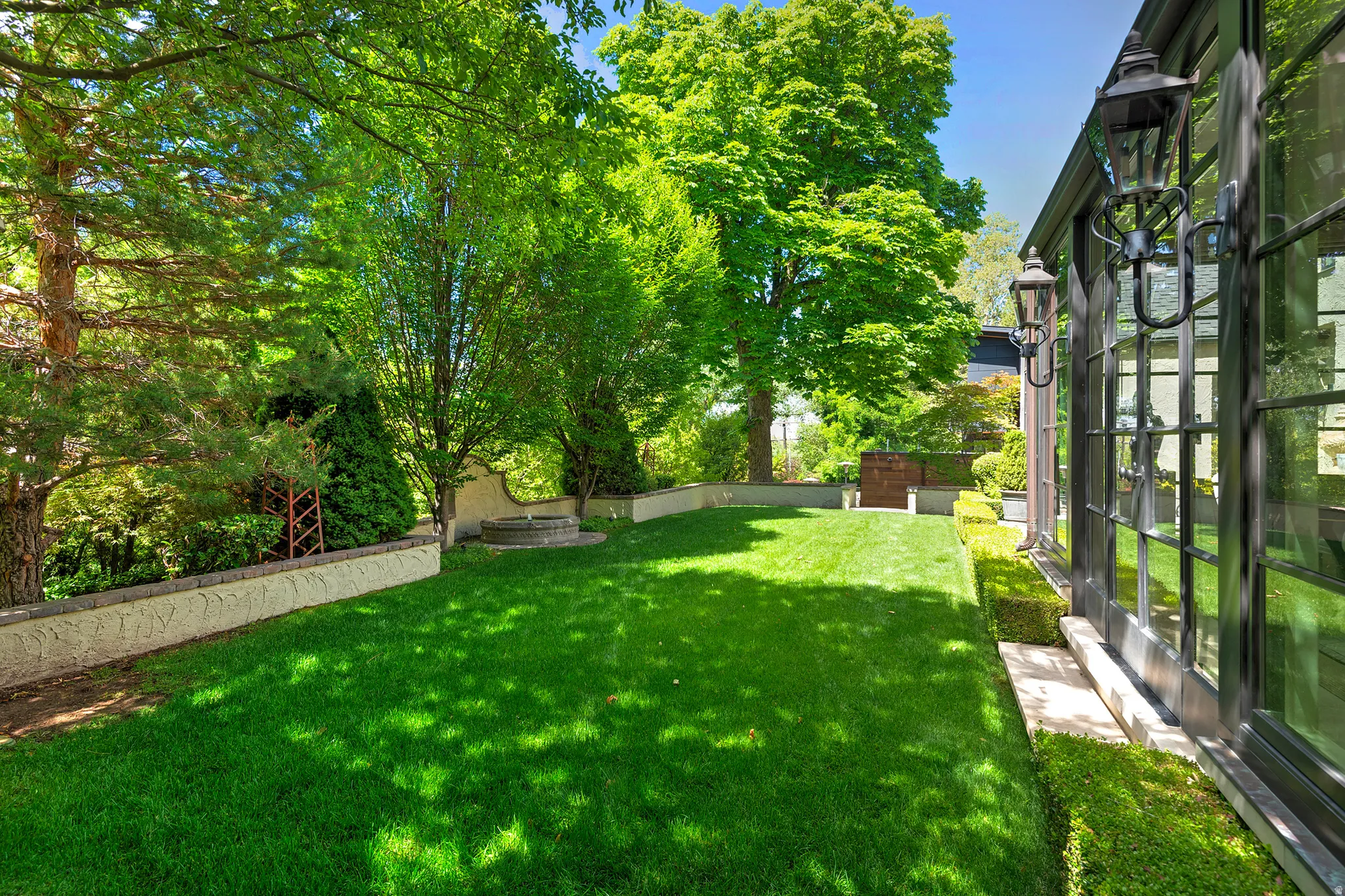Expansive green lawn bordered by mature trees and lush landscaping