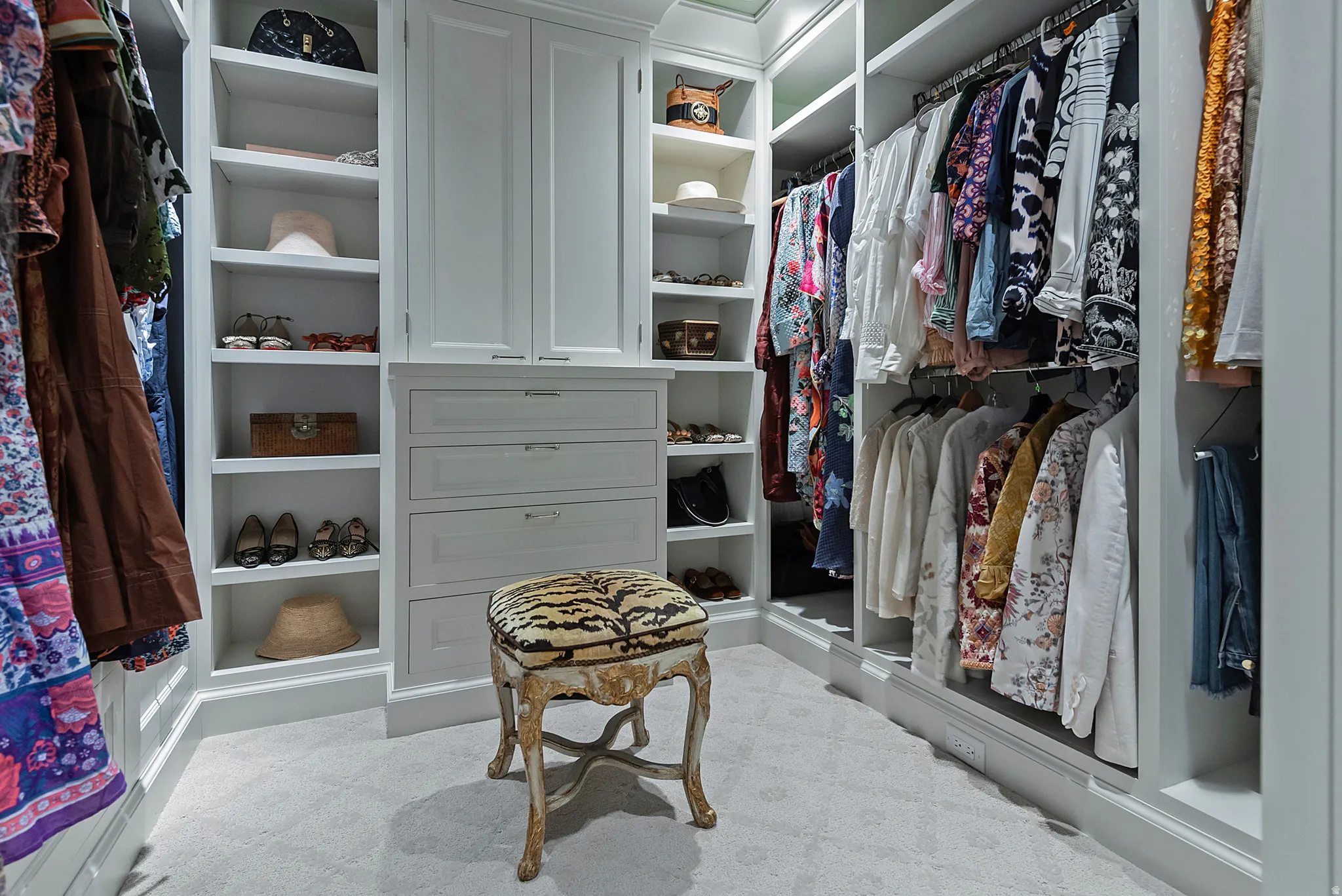 Built-in custom cabinetry with integrated shelving, multiple hanging rods, and pull-out drawers