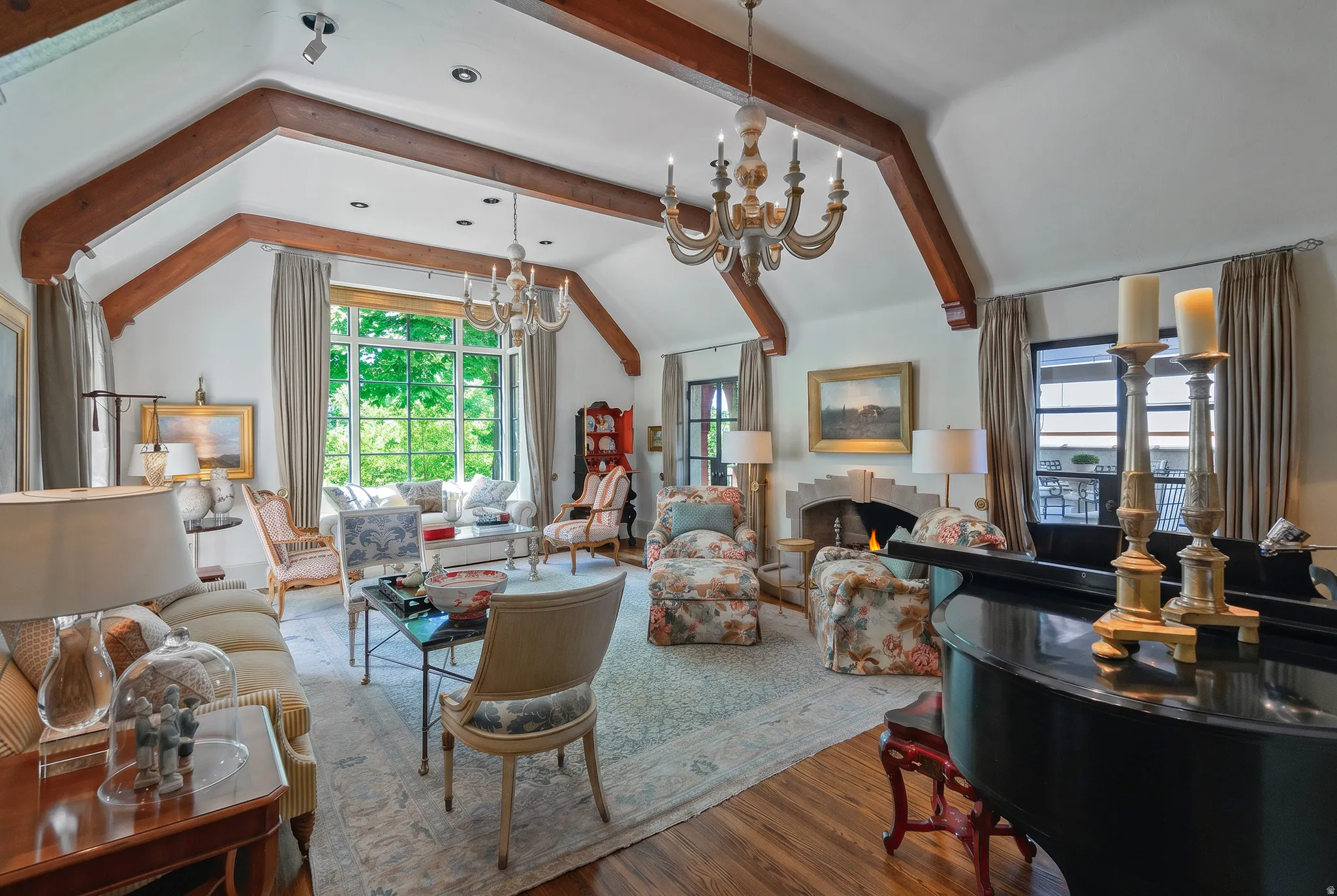 Vaulted ceiling with exposed wood beams, a stone-faced fireplace, and hardwood flooring