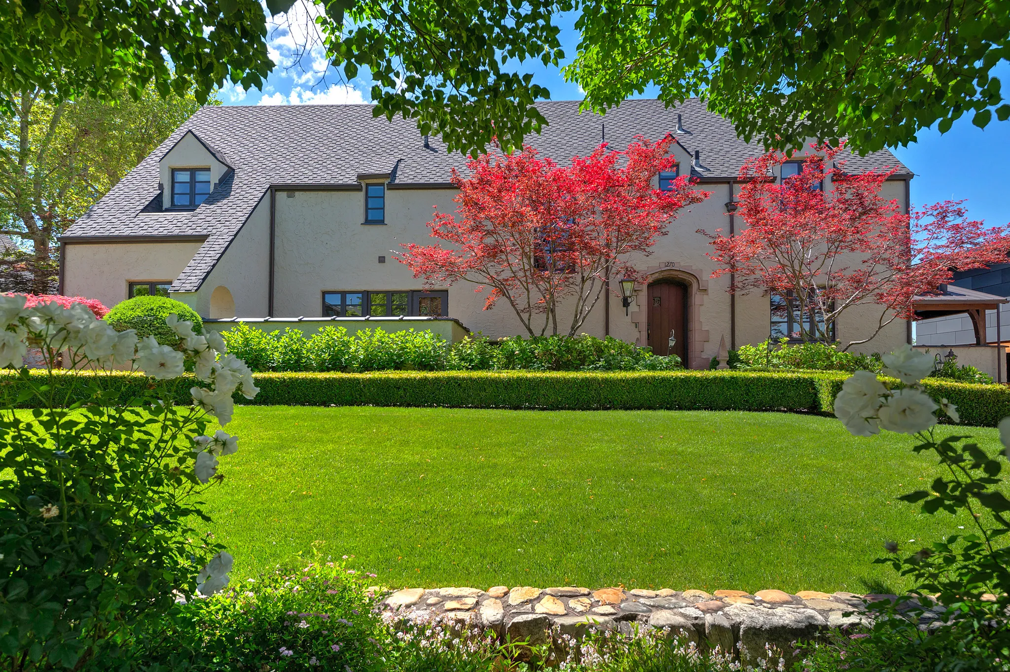 Stucco exterior residence featuring a dark shingle roof and dormer windows