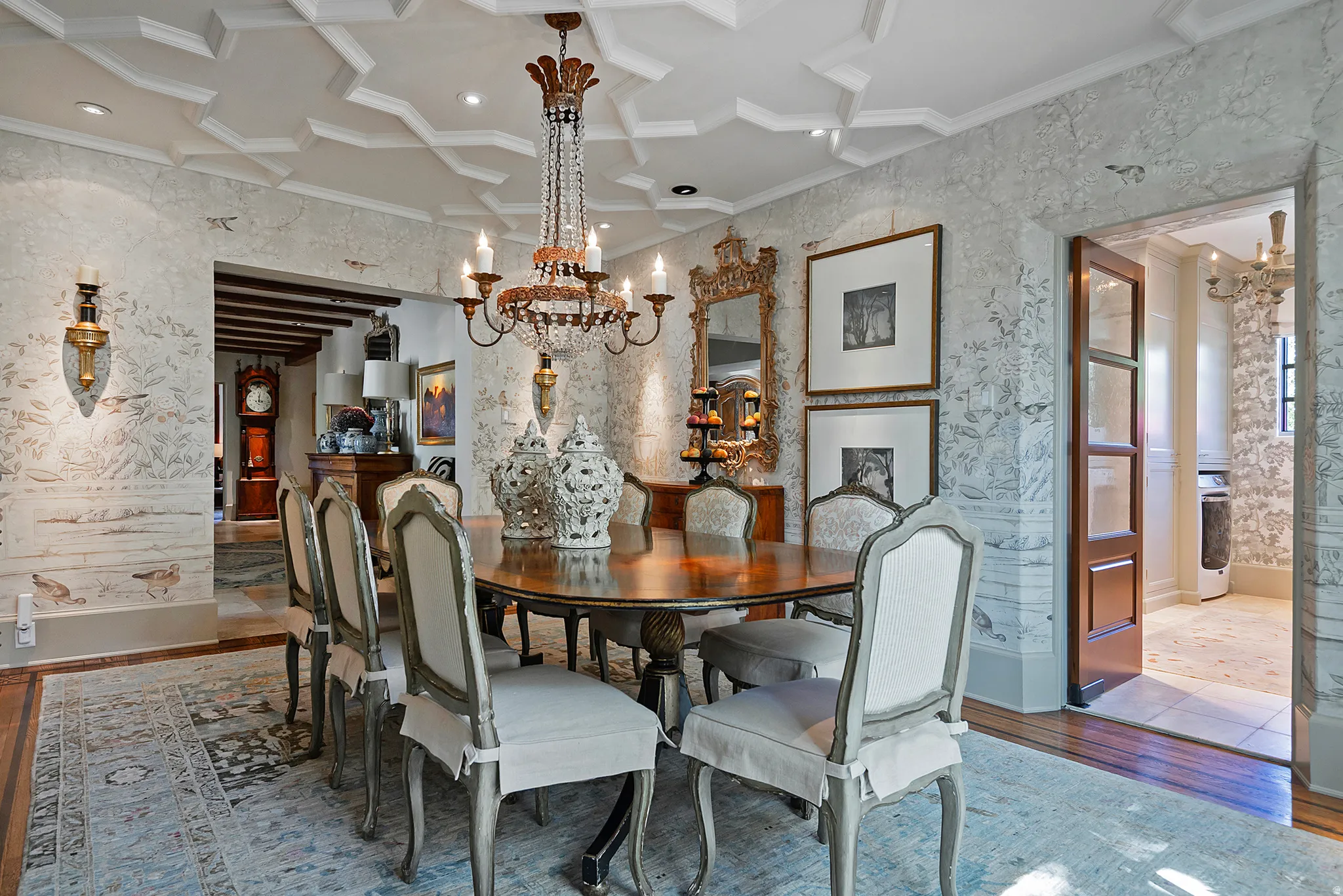 Dining area featuring a coffered ceiling, crystal chandelier, decorative wall sconces, wood flooring, and an arched entryway